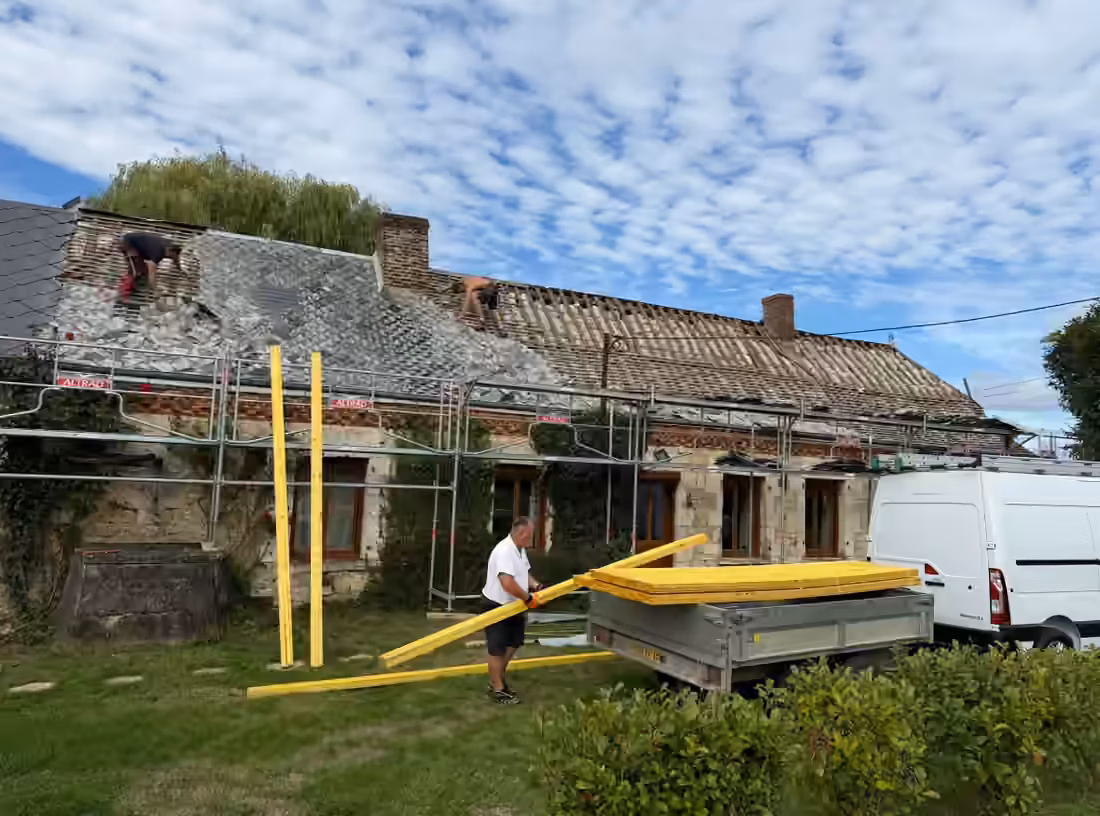 Réfection d’une couverture : anciennes ardoises en dépose, échafaudage et liteaux au pied de la maison